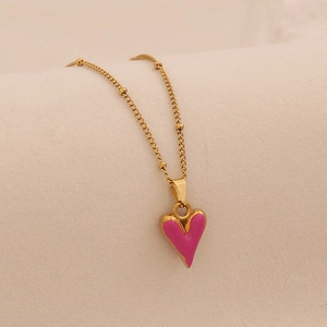 Détail du collier doré avec pendentif cœur en émail rose et petites billes dorées fines