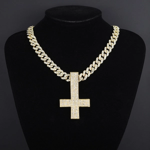Detailed view of a gold plated Cuban chain necklace with iced-out inverted cross pendant