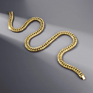 Close-up of a 12mm golden curb chain with polished finish on a grey textured surface