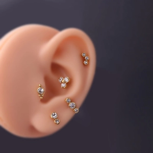 Golden 20G stainless steel helix studs set with clear cubic zirconia on ear model
