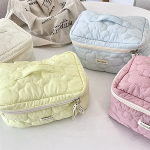 Close-up of heart quilted makeup bags showing soft texture and premium zipper detail