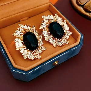Details von Vintage-Ohrringen in Gold mit hohlem Blattdesign und schwarzem ovalem Edelstein