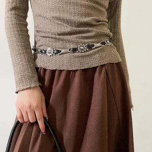 Close-up of Bohemian leather belt with sunflower metal ornaments worn by a model