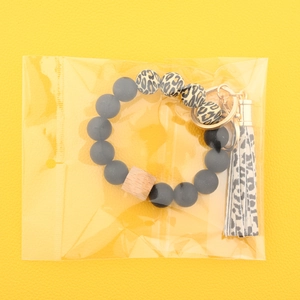 Détail du porte-clés en perles de silicone avec pompon léopard sous emballage plastique