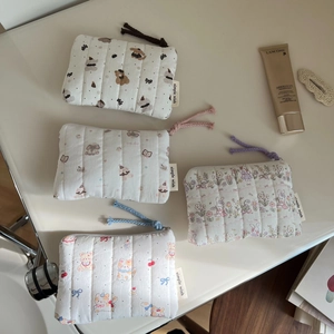 Detailed macro view of quilted cotton pouches with cute animal prints and colorful zippers