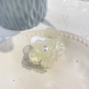 Detailed close-up of cream floral hair claw clip featuring elegant pearl accents