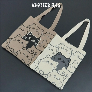 Detailed view of beige and off-white knitted tote bags featuring cartoon cat patterns