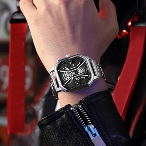Close-up of silver square skeleton watch with metallic strap worn on a wrist