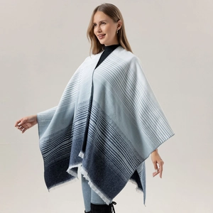 Close-up of blue and white gradient knitted poncho featuring fringe trim and striped pattern