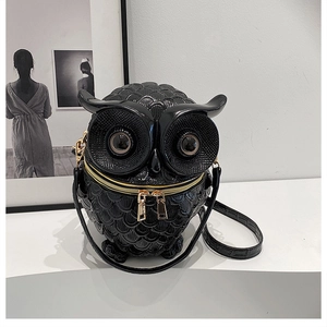 Detail of creative black owl-shaped crossbody bag featuring textured glossy finish