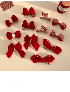 Close-up of red velvet bow hairpins with pearls, plush cat ears, and festive decorations