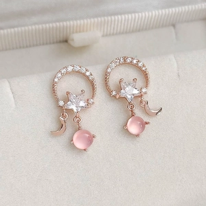 Macro shot of rose gold star and moon earrings with cubic zirconia and pink cat eye stones