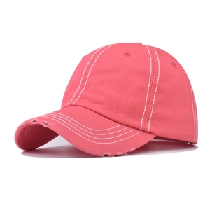 Detailed close-up of pink distressed cotton baseball cap with white contrast stitching