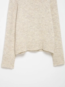 Close-up of thick knit wool blend texture with ribbed hem and cuff on sweater