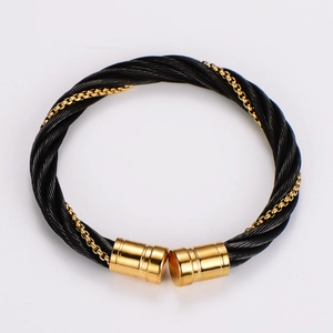 Macro detail of black steel cable weave and gold-plated clasp on a hip hop bracelet