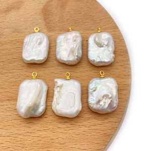 Baroque rectangle freshwater pearl pendants with gold rings on a wooden tray