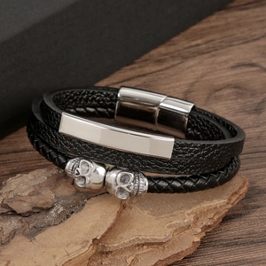 Gros plan d'un bracelet en cuir noir tressé avec des crânes en argent sur bois