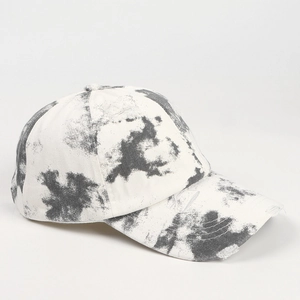 Close-up of tie-dye ink patterns and distressed frayed edges on a denim baseball cap