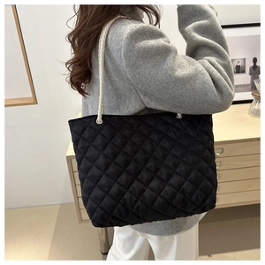 Détail du sac cabas matelassé noir avec anses en corde tressée blanche sur l'épaule