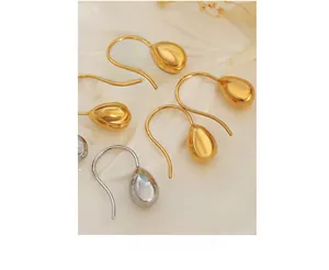 Macro shot of gold and silver teardrop earrings on a white textured ceramic tile