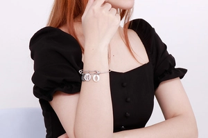 Detailed shot of silver steel charm bracelet with LOVE and female silhouette pendants