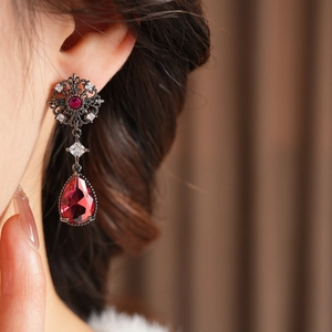 Gros plan de boucles d'oreilles vintage en goutte avec cristaux rouges et base florale noire