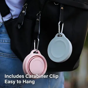 Portable collapsible silicone travel cup with carabiner clip hanging on a black backpack