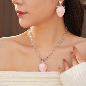 Detailed close-up of pink strawberry pendant necklace and matching resin earrings set