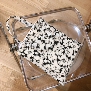 Detailed view of black and white floral cotton tote with front pocket on a chair