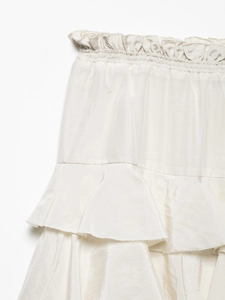 Detail of cream tiered skirt featuring elastic ruffled waist and silky fabric texture