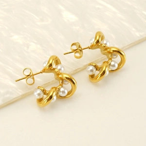 Macro detail of French style 18K gold-plated wave C-shape pearl earrings with a twisted texture