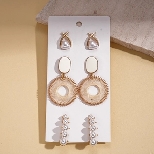 Retro geometric earring set with pearls and gold accents on a warm beige background