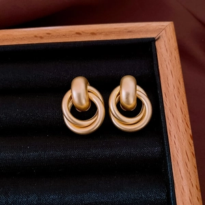 Close-up of vintage matte gold interlocking hoop earrings on a black velvet display
