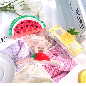 Détail de trois pinces à cheveux en acrylique aux motifs de pastèque d'ananas et de fraise