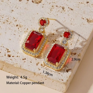 Detailed view of gold copper earrings with red emerald-cut zircon and white gems
