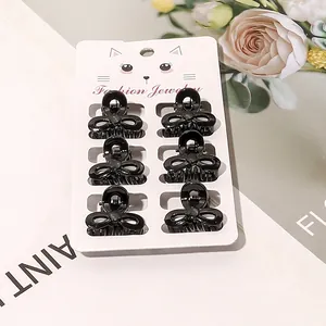 Set of six small black bow-knot hair claws displayed on a decorative jewelry card