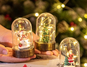 Miniature glass dome Christmas light with snowman held in hand showing compact size