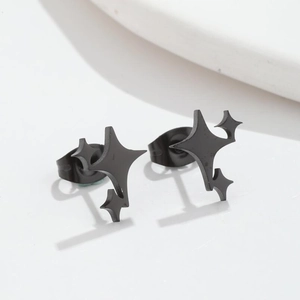 Macro detail of minimalist black matte four-pointed star stud earrings on white surface