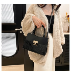 Elegante borsa a mano nera con motivo a coccodrillo e fibbia dorata sulla modella