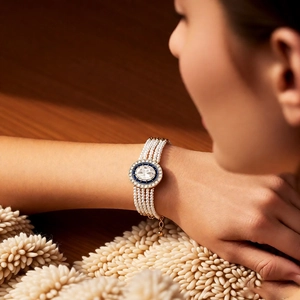 Detail of multi-strand pearl bracelet featuring an oval sapphire center with clear stones