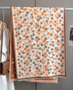 Detail of floral printed scarf with orange leaf patterns and decorative tassel fringe