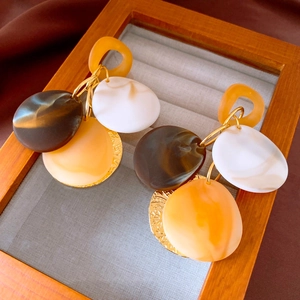Detailed close-up of retro bohemian earrings with resin marble discs and gold textured discs