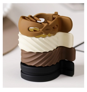 Detail of four matte shark clips in brown, beige, and black for secure ponytail styling
