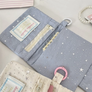 Close-up of canvas card wallets with silver star patterns, zippers, and hanging hooks