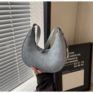 Close-up of light grey crescent shoulder bag with suede texture and silver hardware details