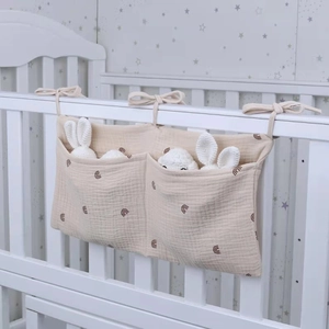 Detail of a double-pocket cotton crib organizer bag with rainbow prints for baby nursery