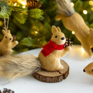 Flocked squirrel Christmas ornaments with red scarves on festive pine tree background