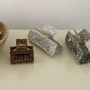 Detailed view of rectangular hair claws featuring leopard print and dalmatian spot patterns