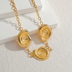 Golden necklace with triple spiral shell pendants on a thick chain over geometric stones
