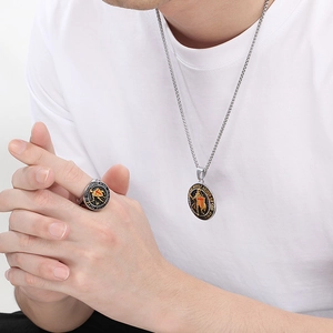 Détail du collier et de la bague en acier argenté avec croix rouge et écriture gravée